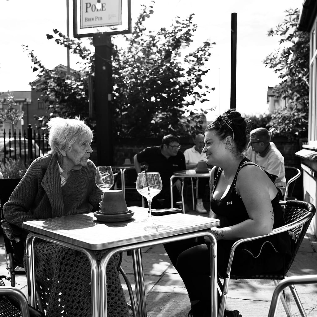a old woman and a young woman sitting at a table drinking Gin