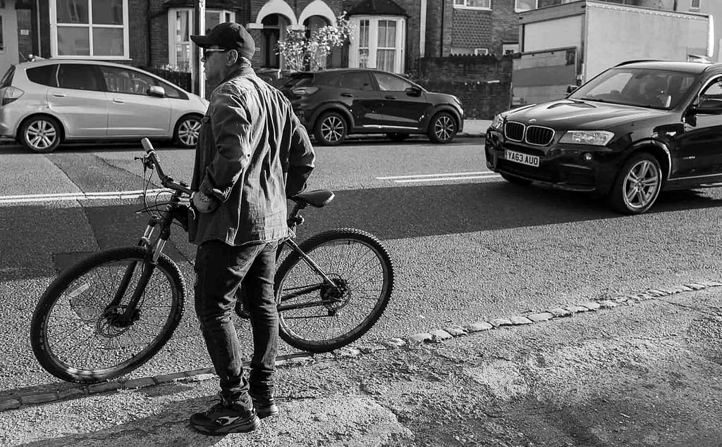 a man standing on a sidewalk with a bicycle